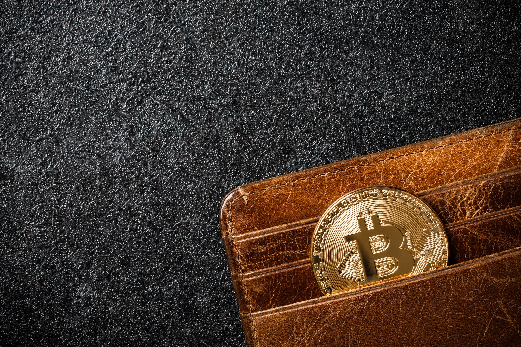 Bitcoin coin in wallet on black background