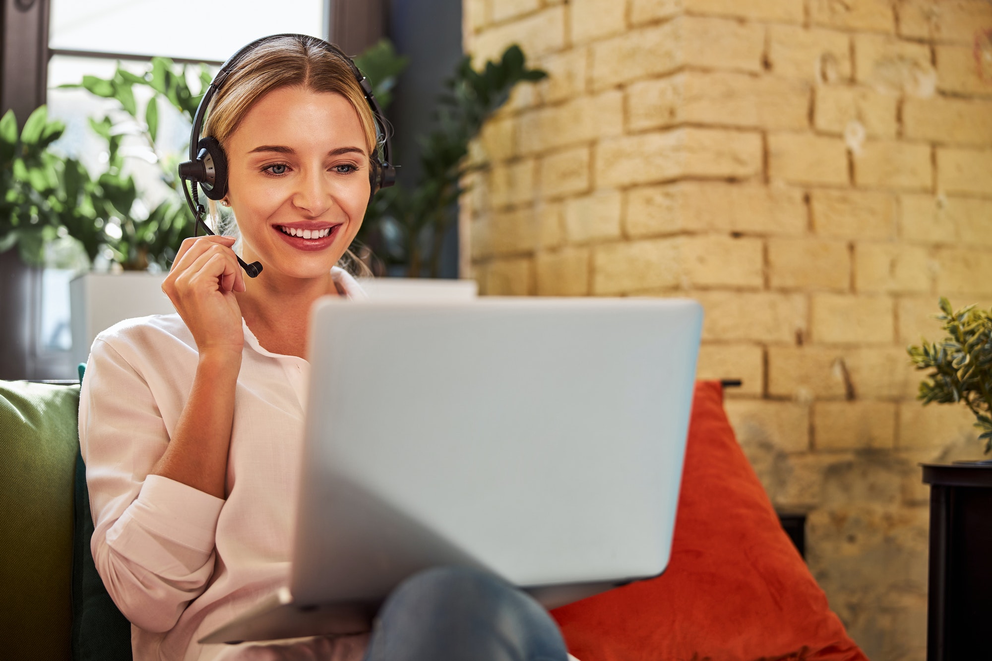 Charming business lady in headphones talking with business partner on laptop